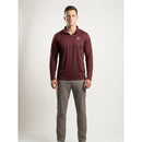 A man modeling a long-sleeve quarter-zip pullover in maroon with a small white logo on the left chest, paired with gray pants, against a light gray studio background.