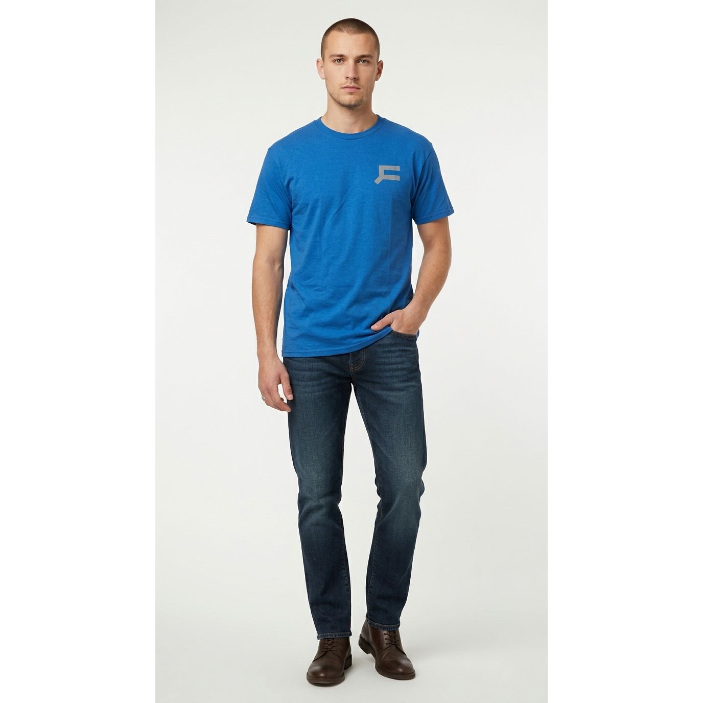 Man wearing a blue t-shirt with a logo and dark jeans on a white background